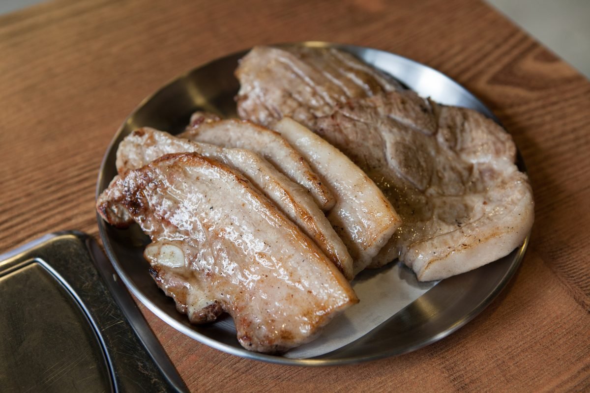 Thick slices of grilled samgyeopsal pork belly on a metal plate