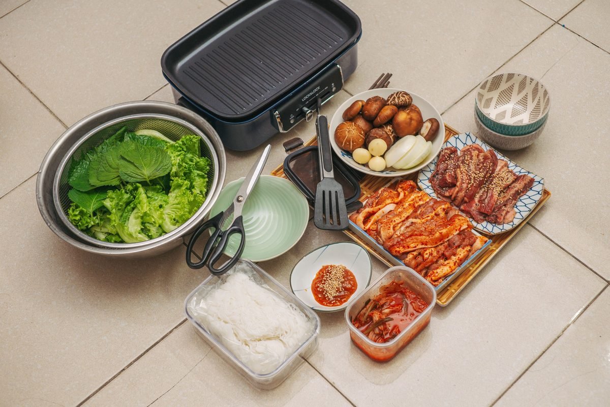 Complete Korean BBQ setup with meat, vegetables, kimchi, and grill