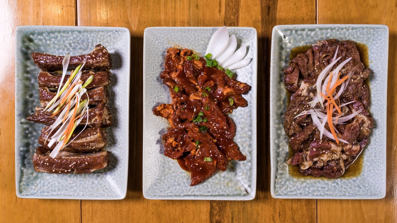 Assorted Korean BBQ meats on plates ready for grilling