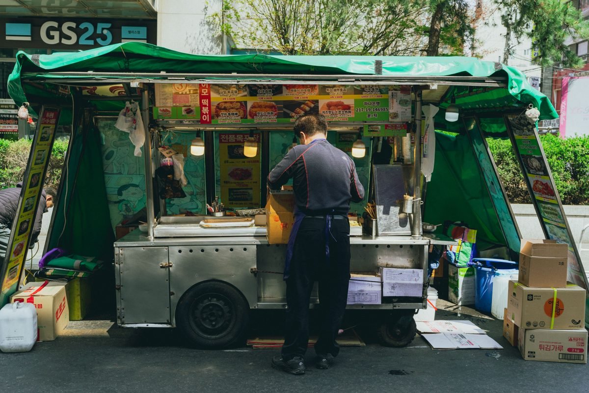 Street food stall in Seoul with a green tarp and GS25 signage in the background