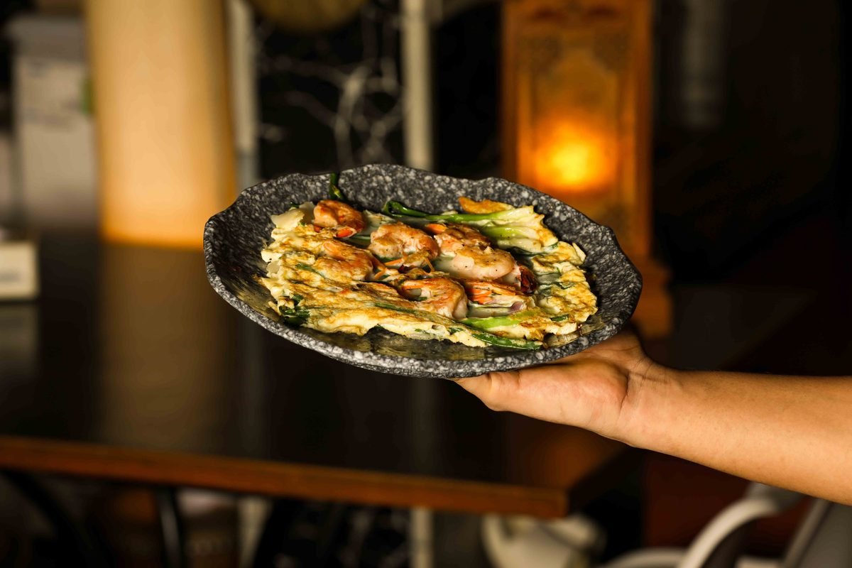 Gourmet seafood pancake served on a dark textured stoneware plate.