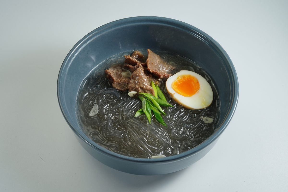 Bowl of Asian glass noodle soup with beef slices and boiled egg.
