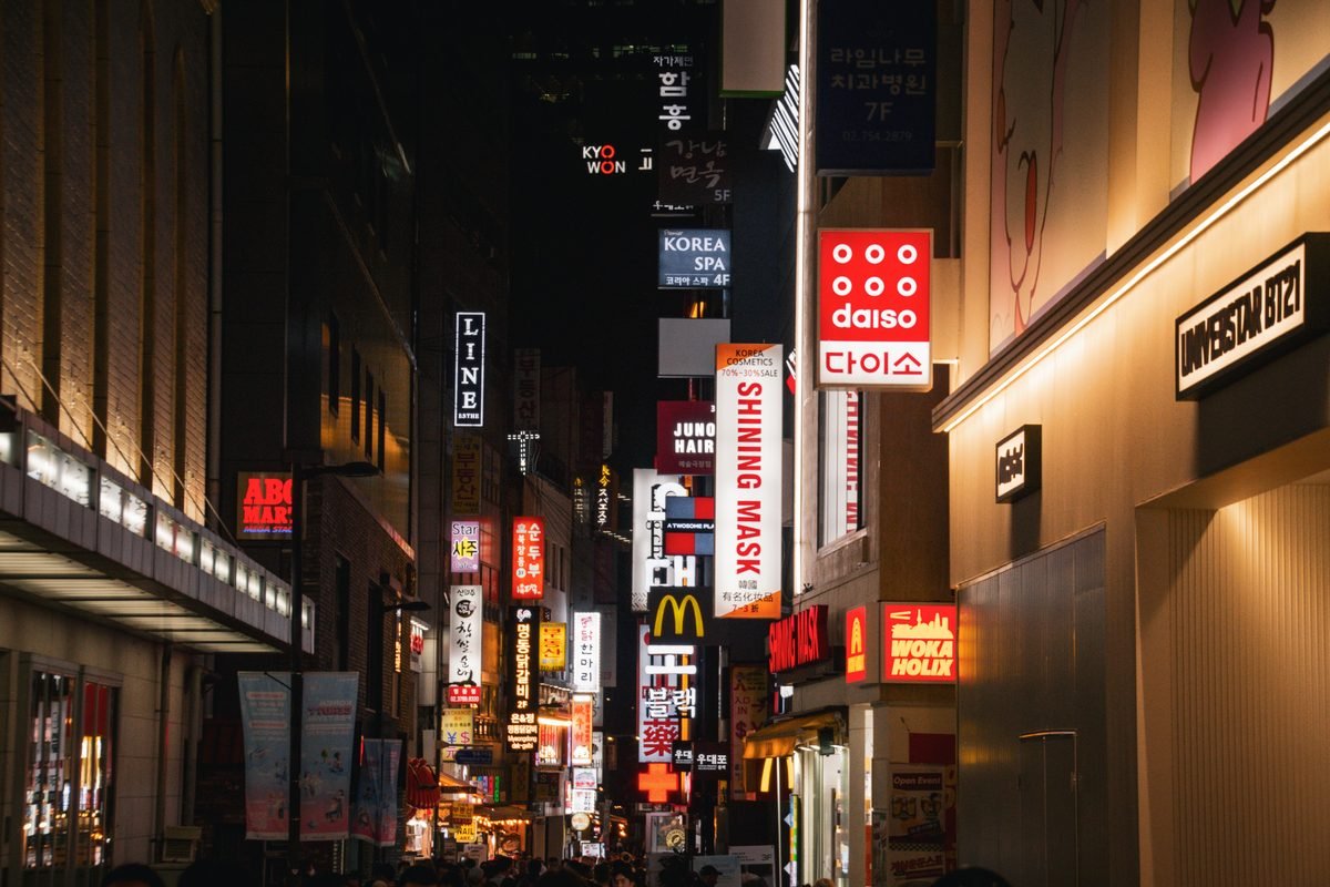 Night view of a busy shopping street illuminated by storefront signs.