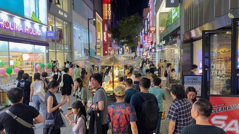 Evening crowds on Myeongdong's cosmetics street, with Holika Holika and Olive Young storefronts lit up