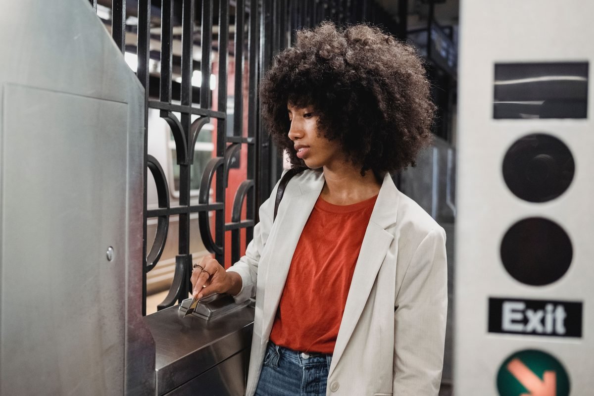 A woman tapping a card on a subway turnstile
