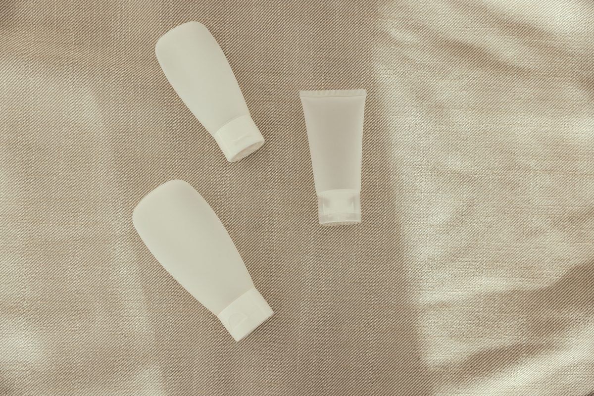 Minimalist plastic squeeze bottles and a tube arranged on a textured surface.