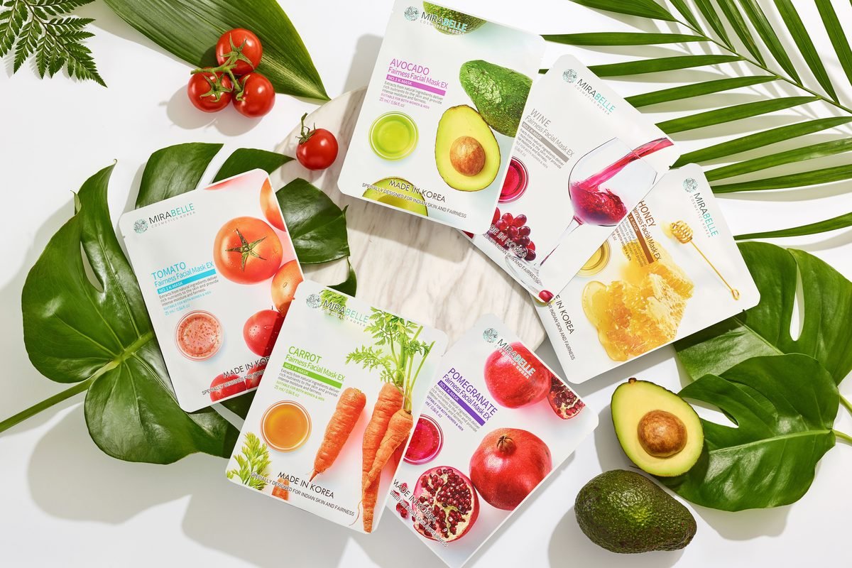 Flat lay composition of Korean sheet mask packages surrounded by fresh produce.