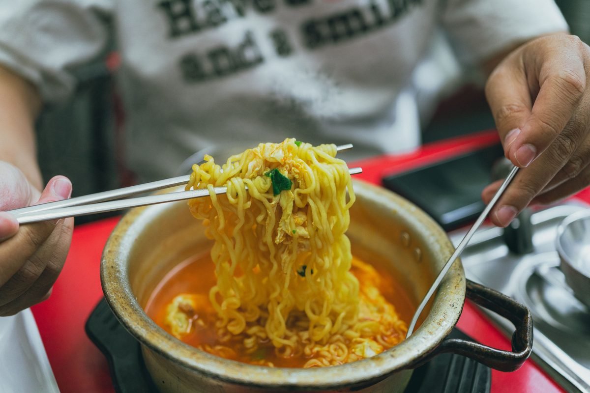 Person eating hot instant noodles with chopsticks in a casual eatery.