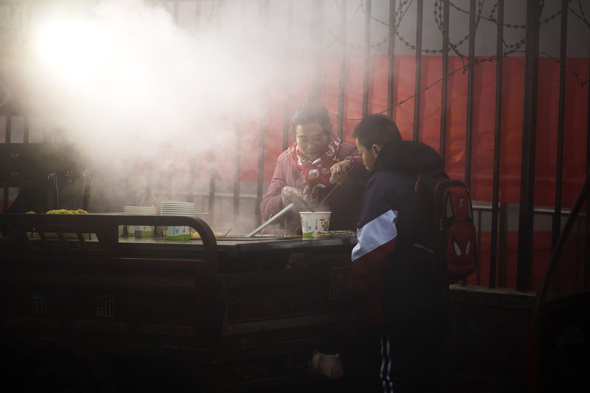 A street vendor cooking food for a customer on a cold foggy day