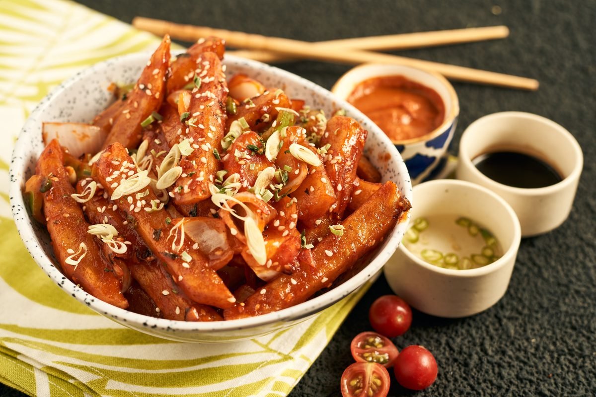 Spicy Korean snack bowl garnished with sesame seeds and dipping sauces