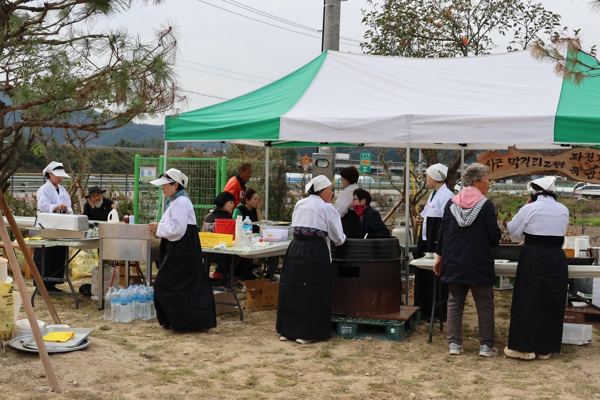 Korean outdoor market stall with people preparing food under a tent