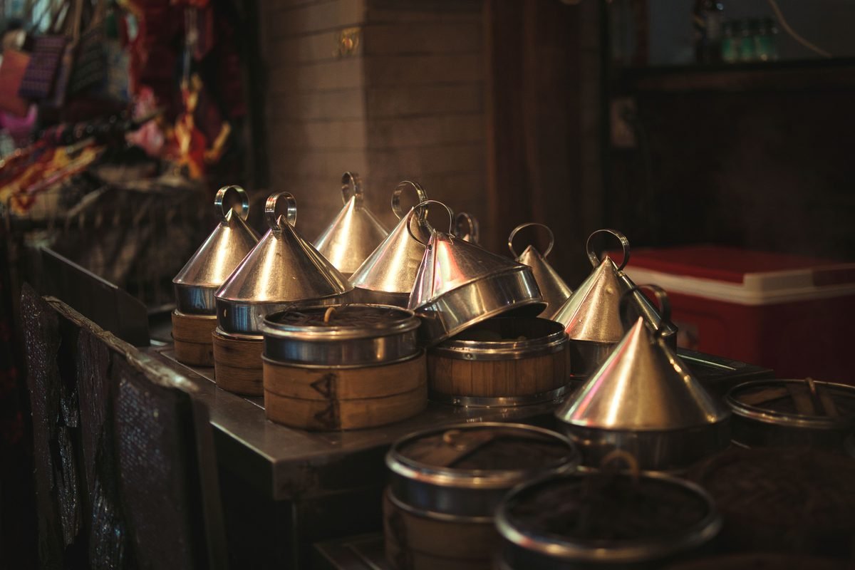 Traditional metal tiffin carriers in dim lighting at an indoor market