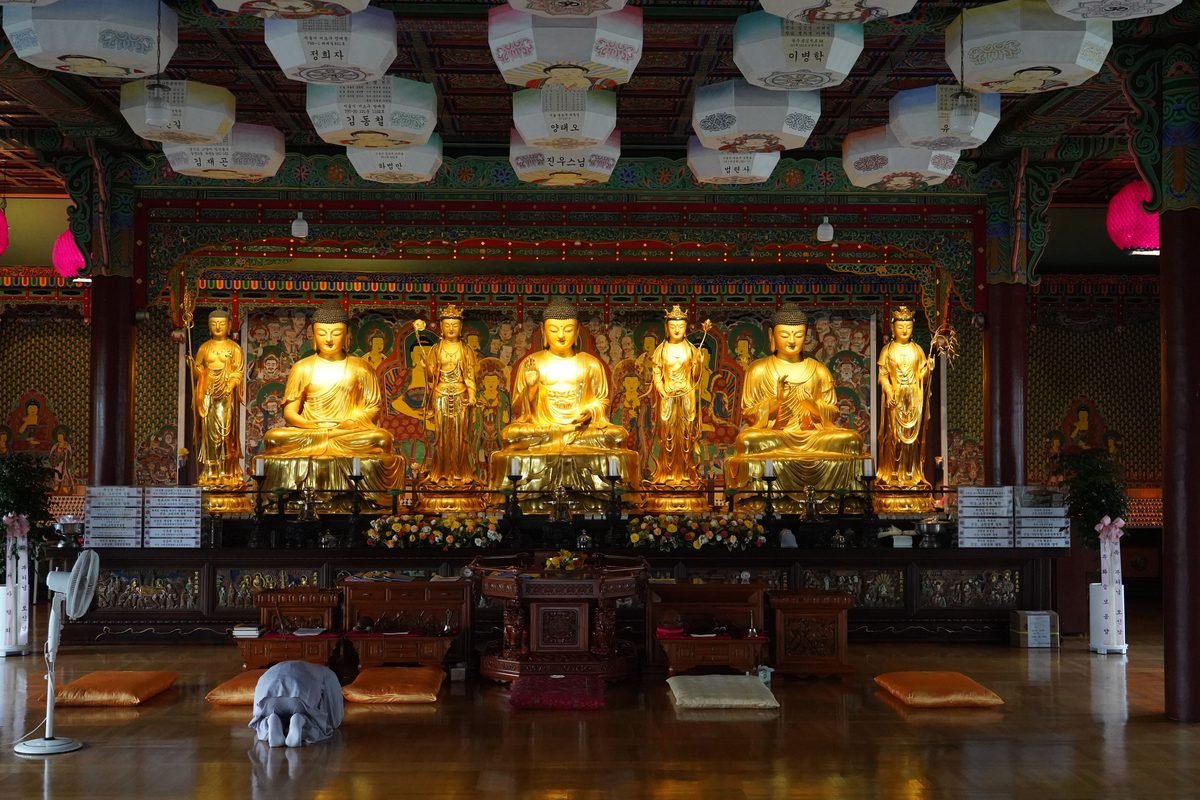 Golden Buddha statues inside a traditional temple with lanterns