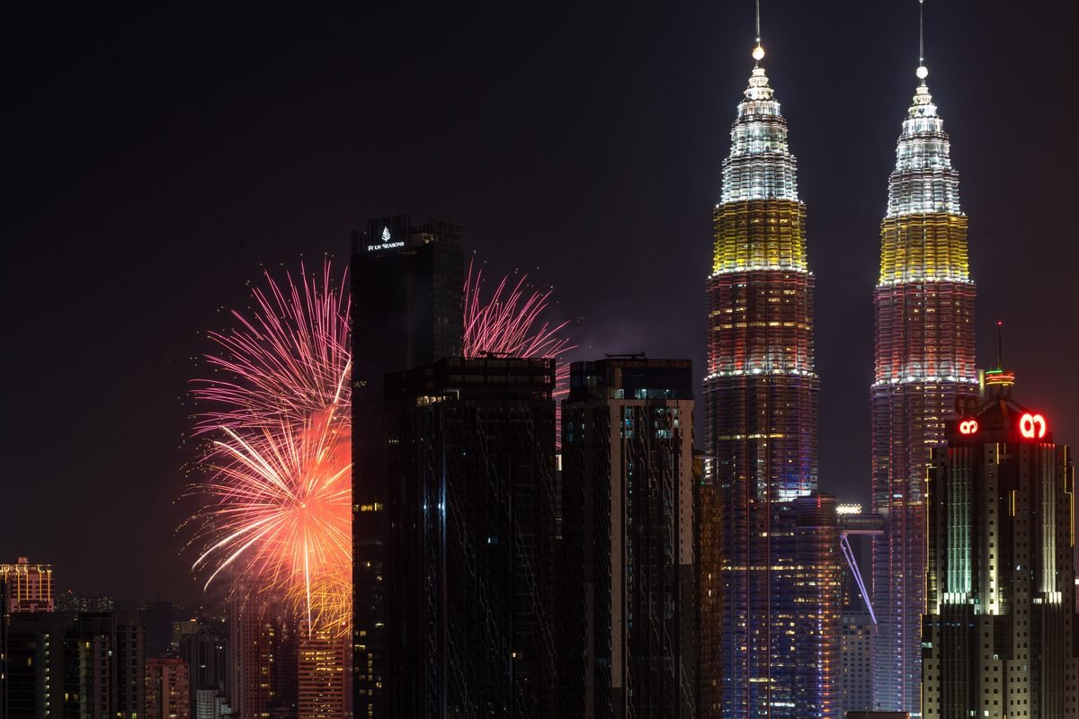Fireworks bursting behind the illuminated Petronas Towers at night