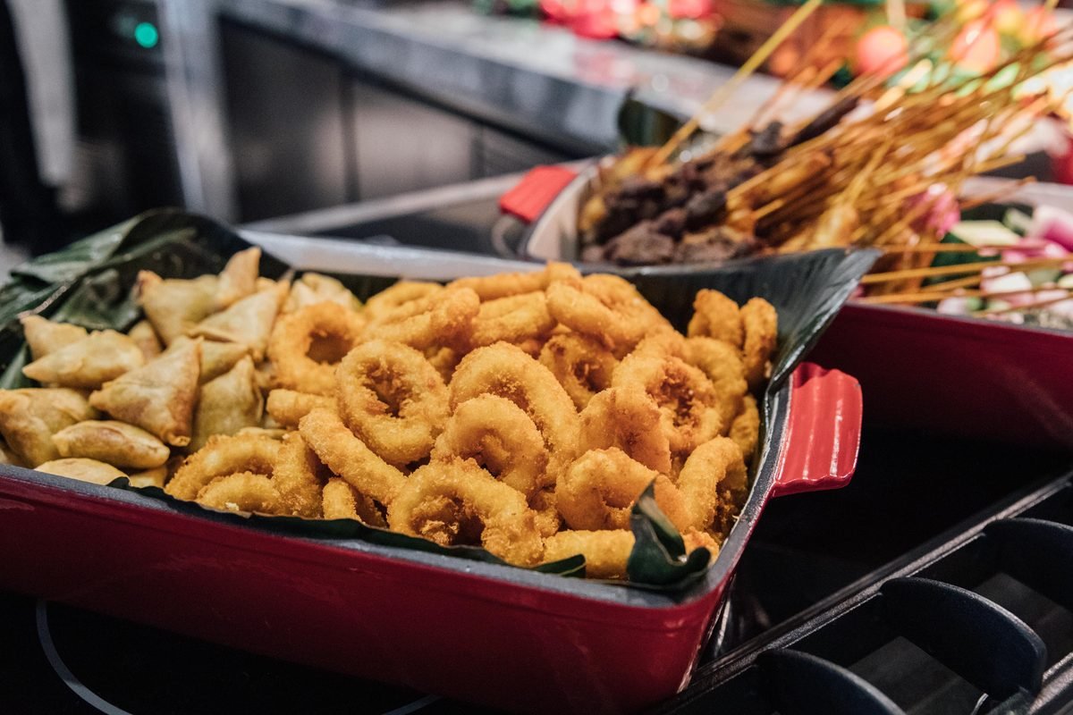 Serving dishes filled with crispy fried snacks and skewers