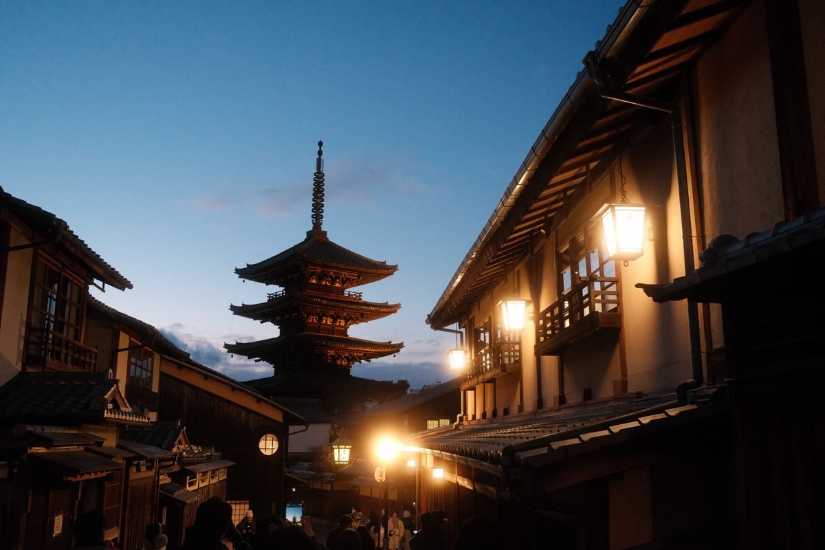Yasaka Pagoda in Kyoto's historic district at dusk with illuminated lanterns.