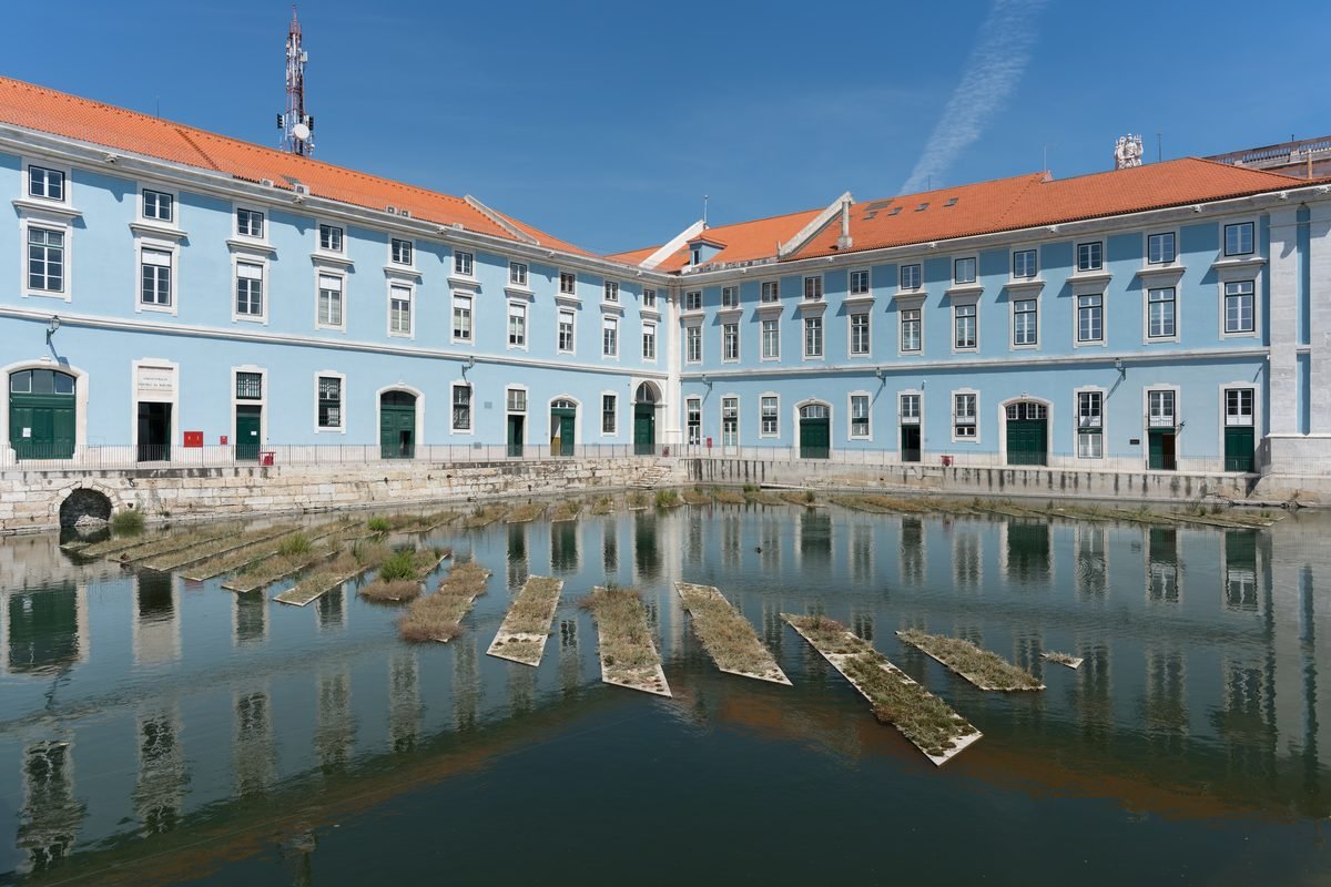 Historic blue building reflecting in the calm water of an old navy dock in Lisbon.