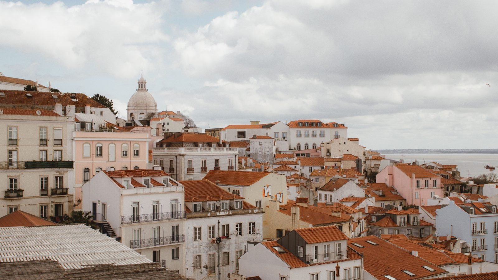 Traditional Lisbon architecture and terracotta rooftops under a cloudy sky.