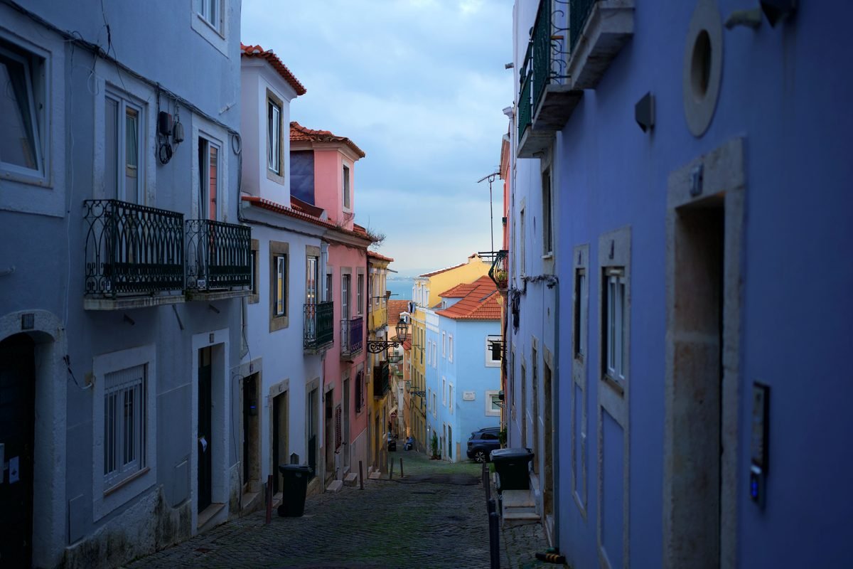 Colorful residential buildings along a narrow sloped street in Lisbon.