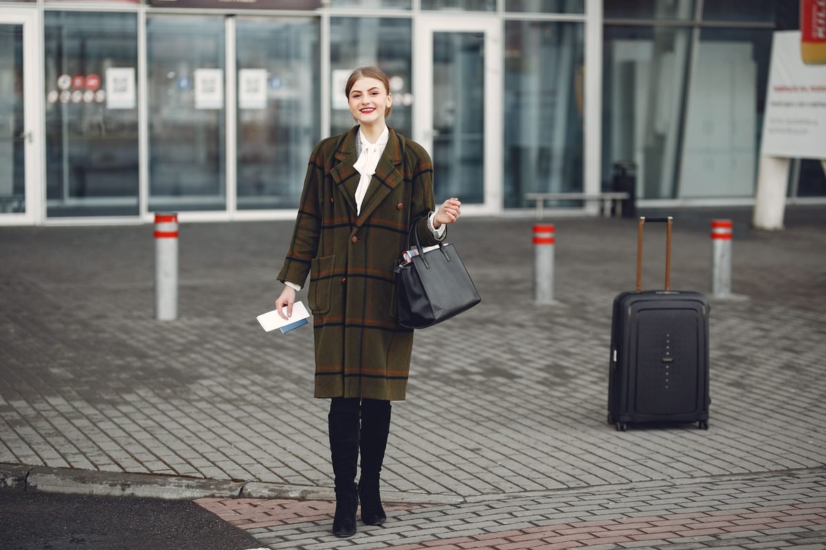Fashionable woman with luggage arriving at an airport ready for travel.