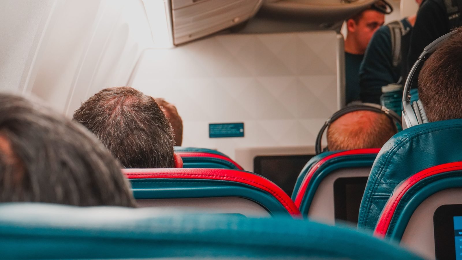 Interior view of an airplane cabin looking down the aisle with seated passengers.