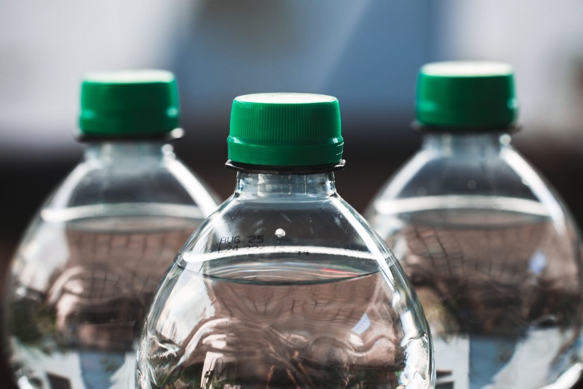 Close-up of three clear plastic water bottles with green caps.