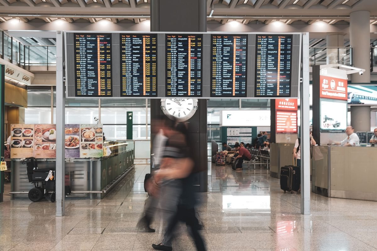 Wide shot of a modern airport terminal departure board with international destinations.