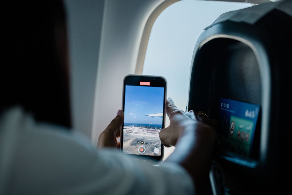 Close-up of a person using a smartphone to view an airplane map while seated.