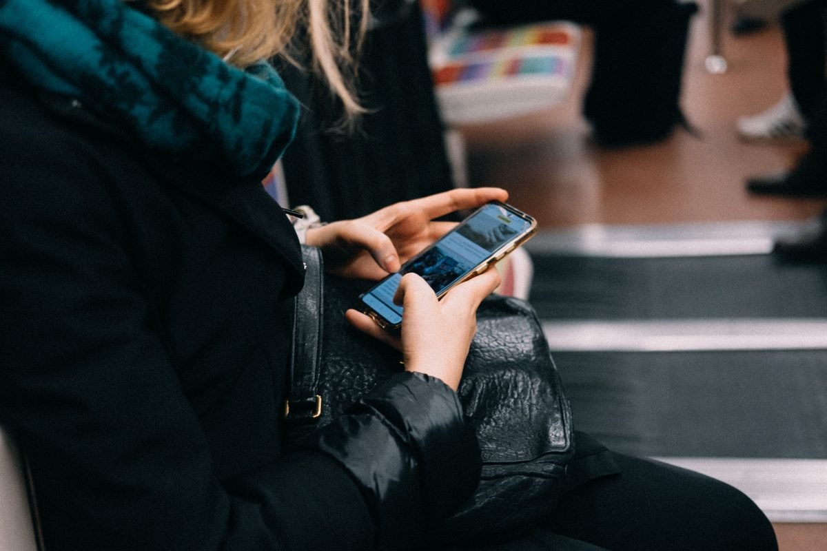 Close-up of a person using a smartphone on public transportation.