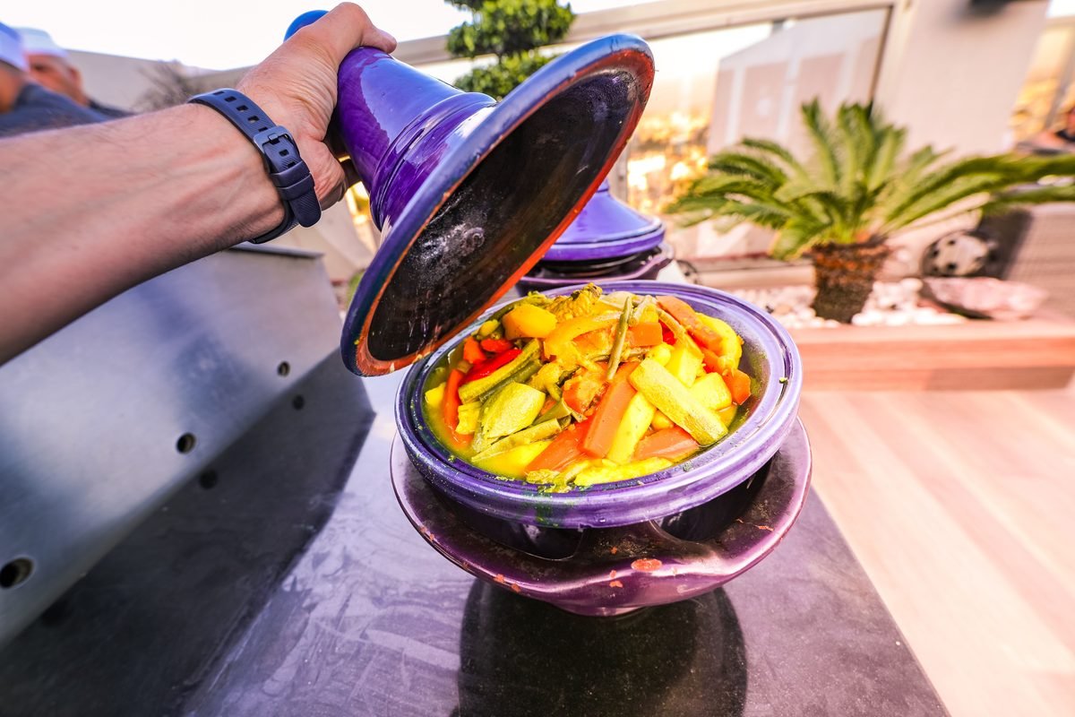 Vegetable tagine being uncovered from a purple pot