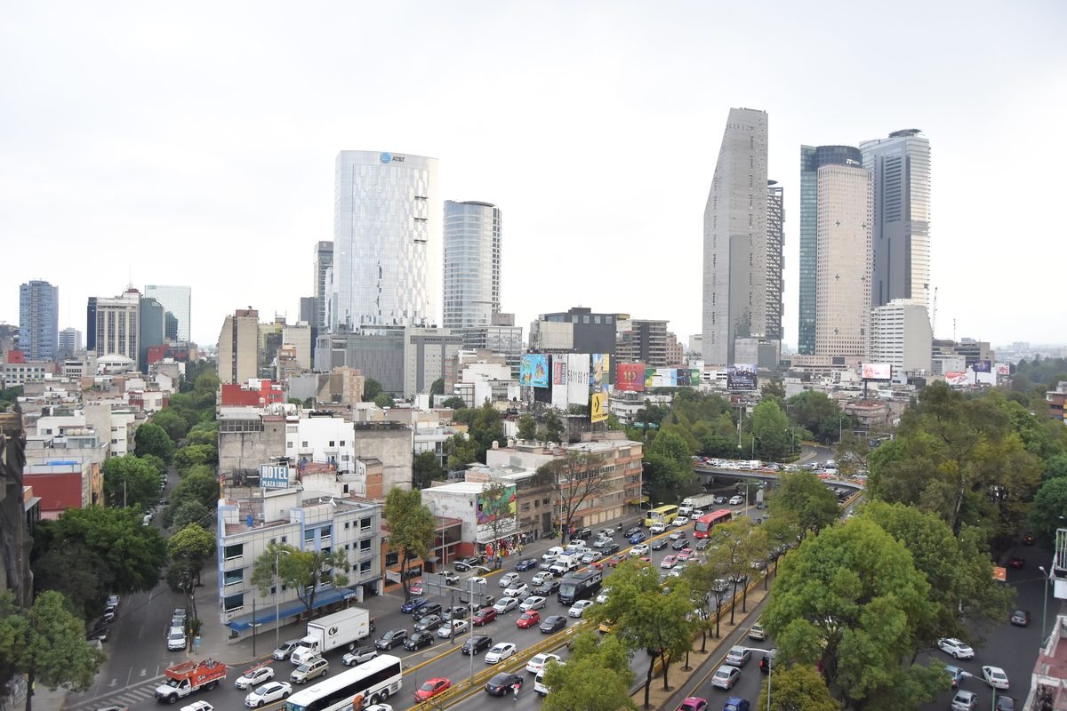 A bustling Mexico City street with skyscrapers and heavy traffic.