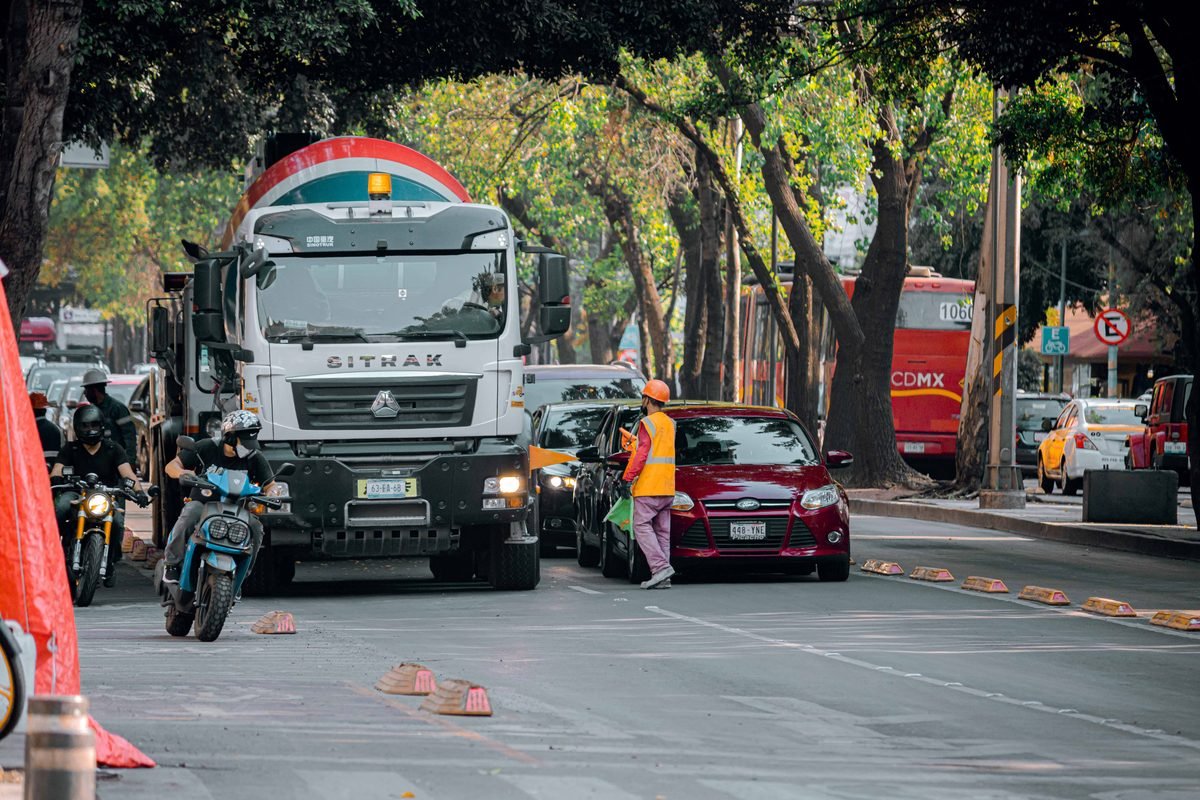 Street view of urban traffic with vehicles and workers in Mexico City.