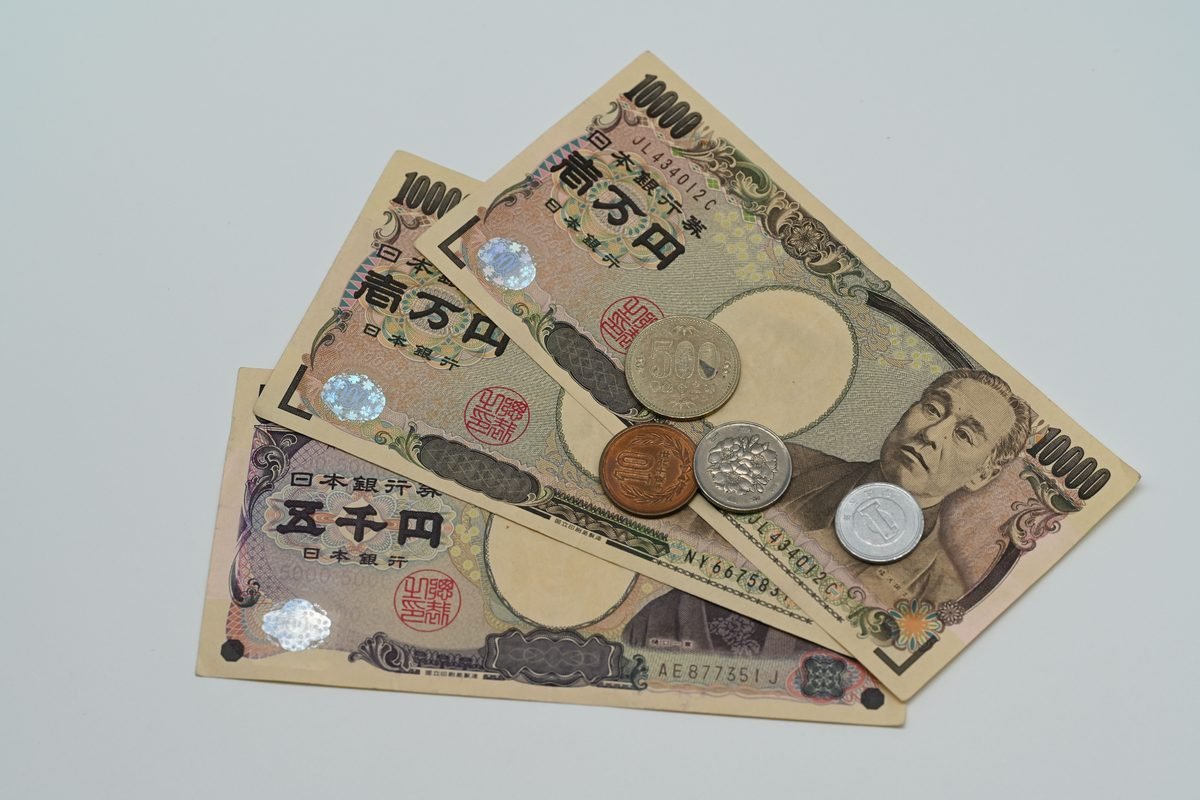 Japanese Yen banknotes and coins neatly arranged on a white surface