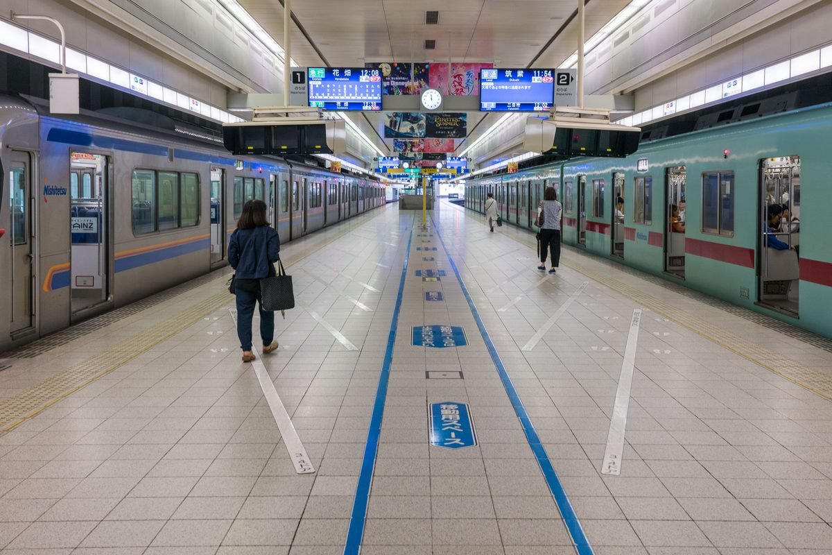 Clean modern Japanese subway station platform with trains parked on both sides.