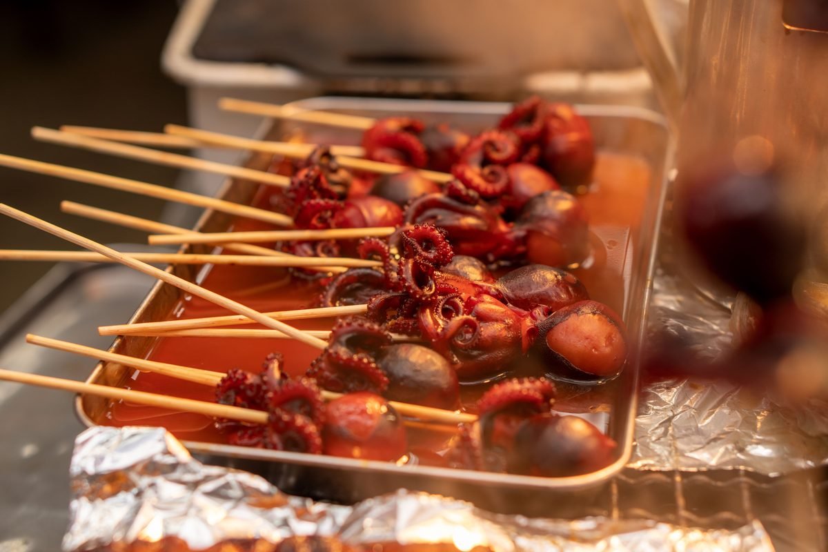 Glazed baby octopus skewers in a tray at a Japanese street food stall