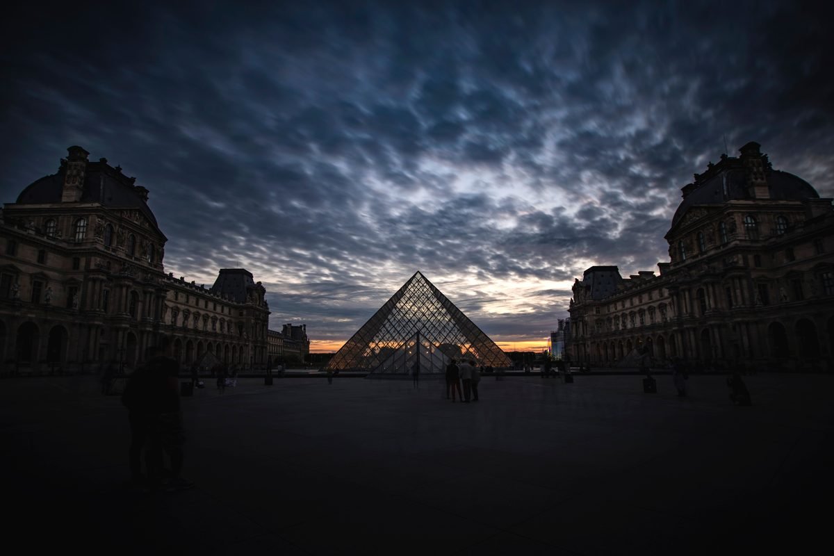 Silhouette of the Louvre Pyramid at sunset with dramatic clouds