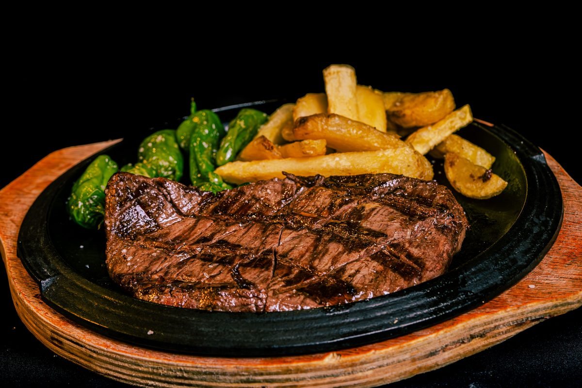 Grilled beef steak served with french fries and peppers