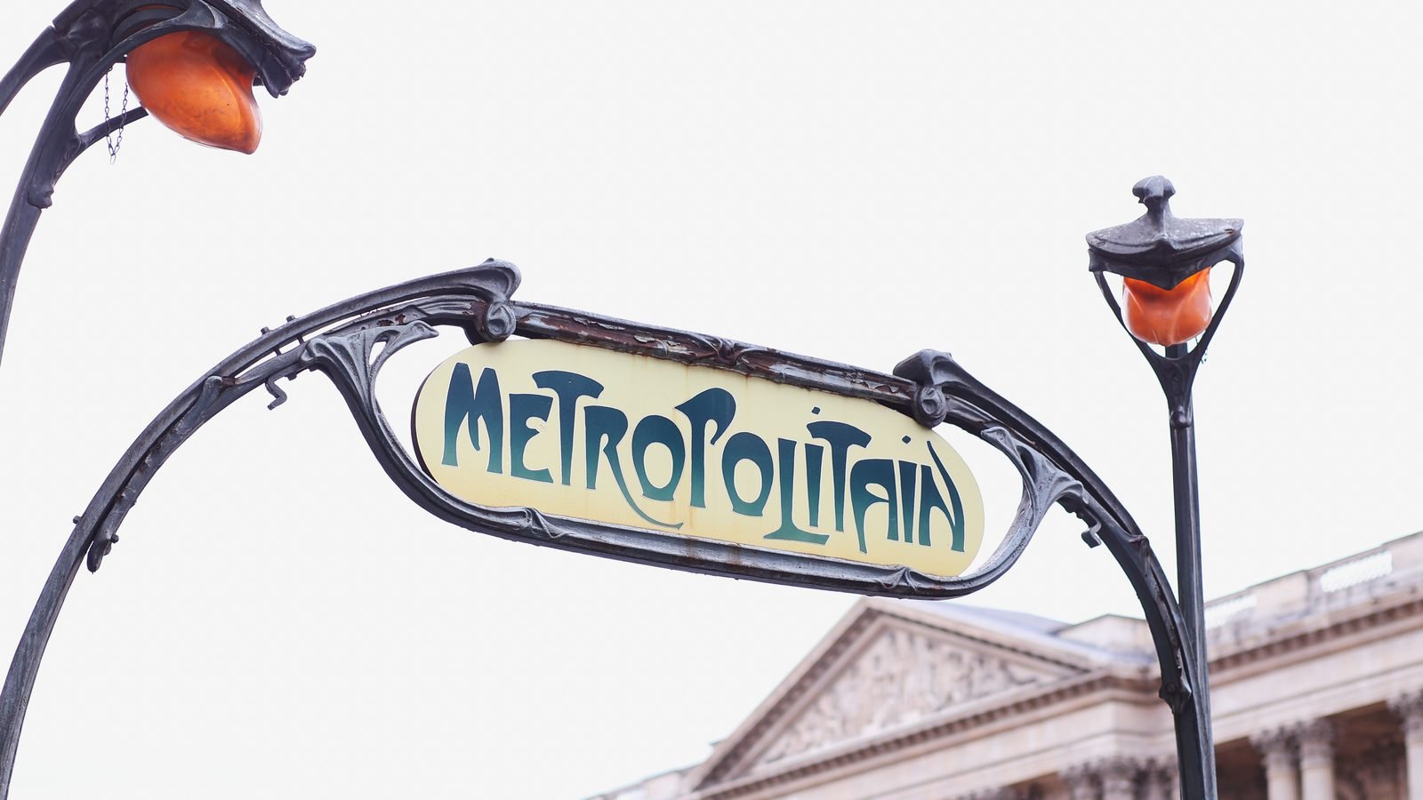 Classic Metropolitain Art Nouveau sign in Paris with historic building in background