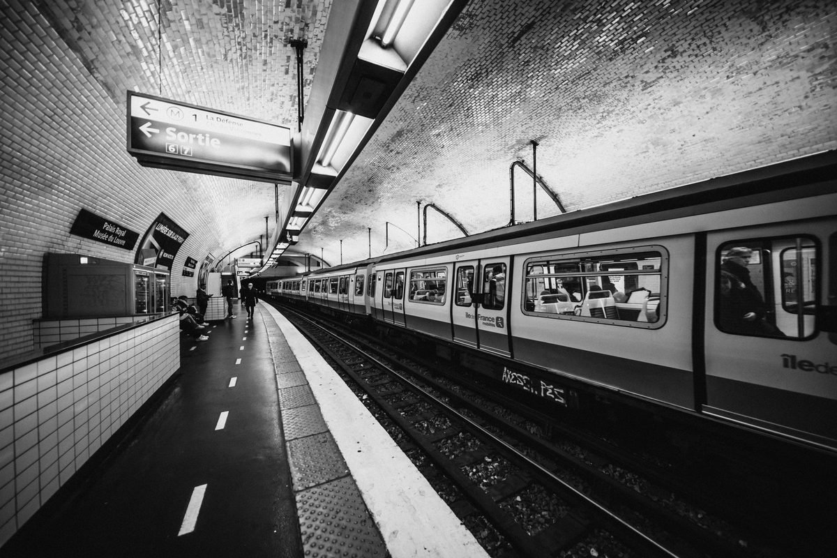 Black and white view of a Paris metro station platform with a train