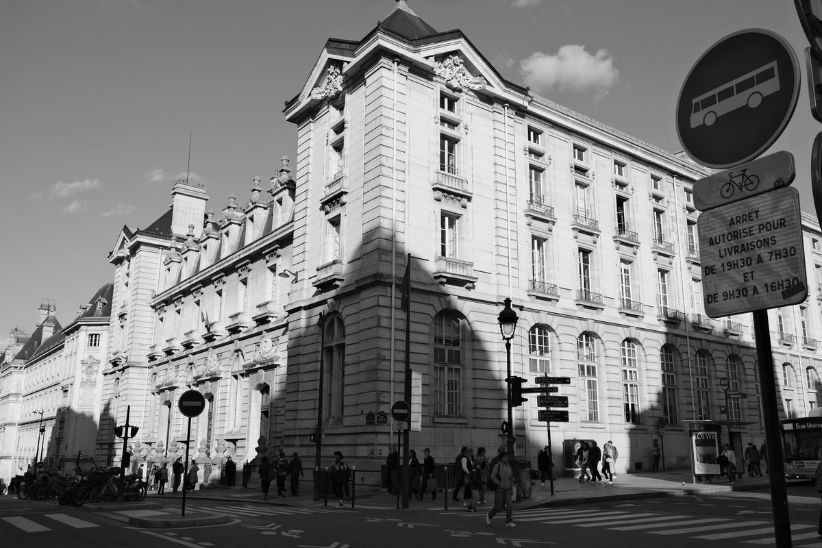 Historic stone building and street sign in Paris with pedestrians