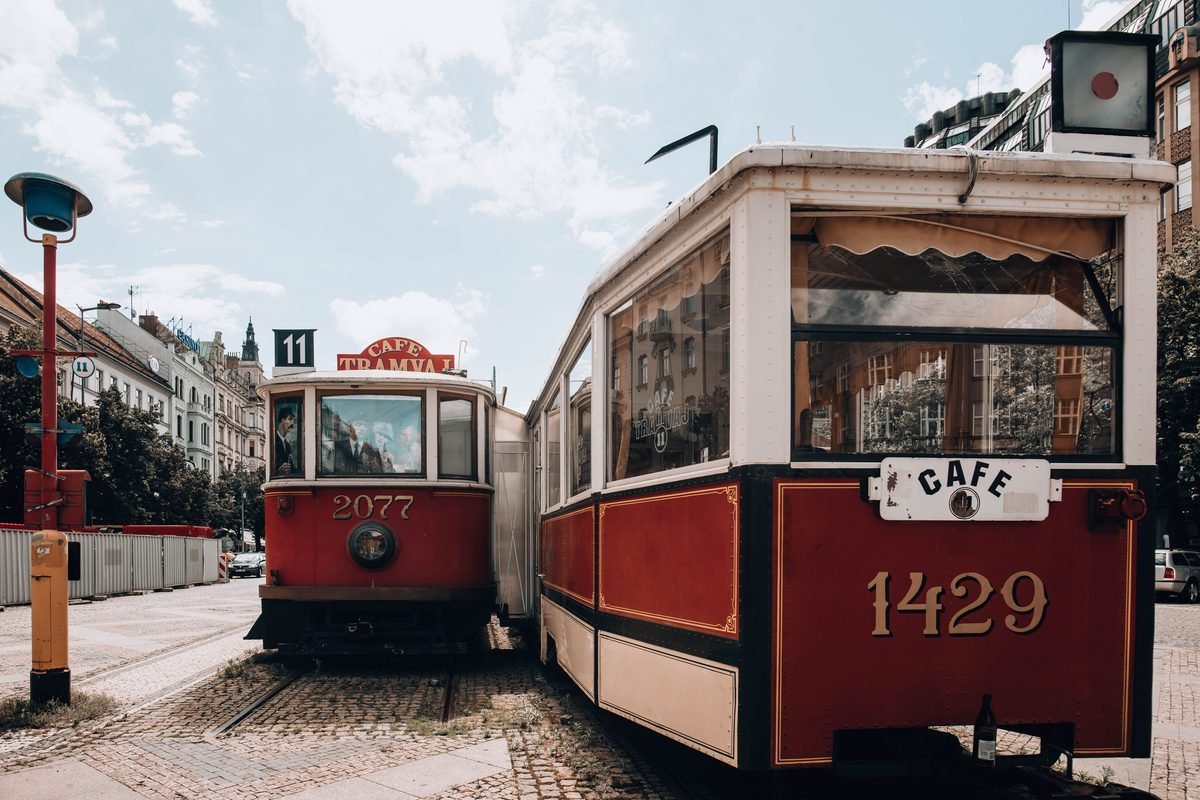 Vintage red trams parked near a café in Prague