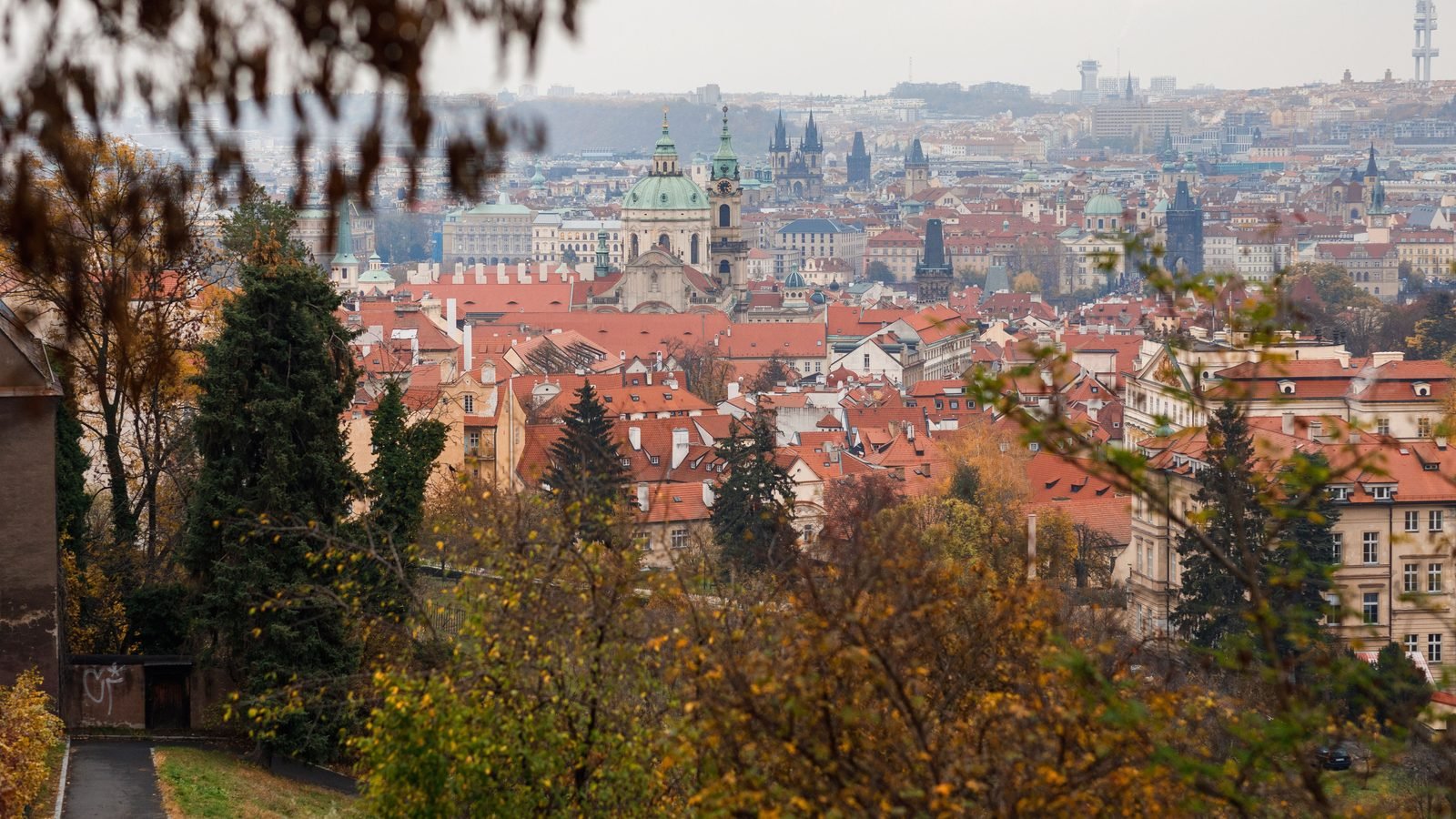 Cityscape of Prague with red roofs and autumn trees