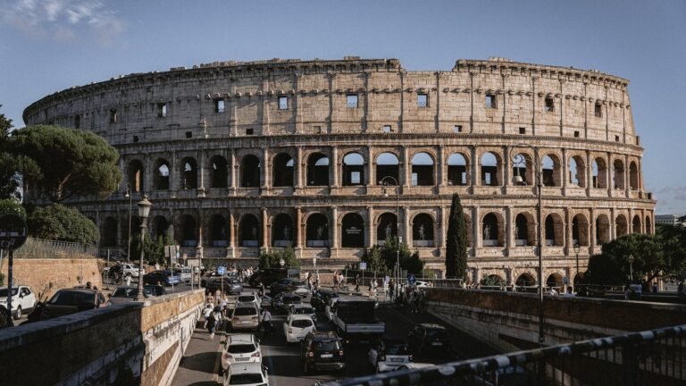 The iconic Colosseum stands majestically under a clear blue sky in Rome.