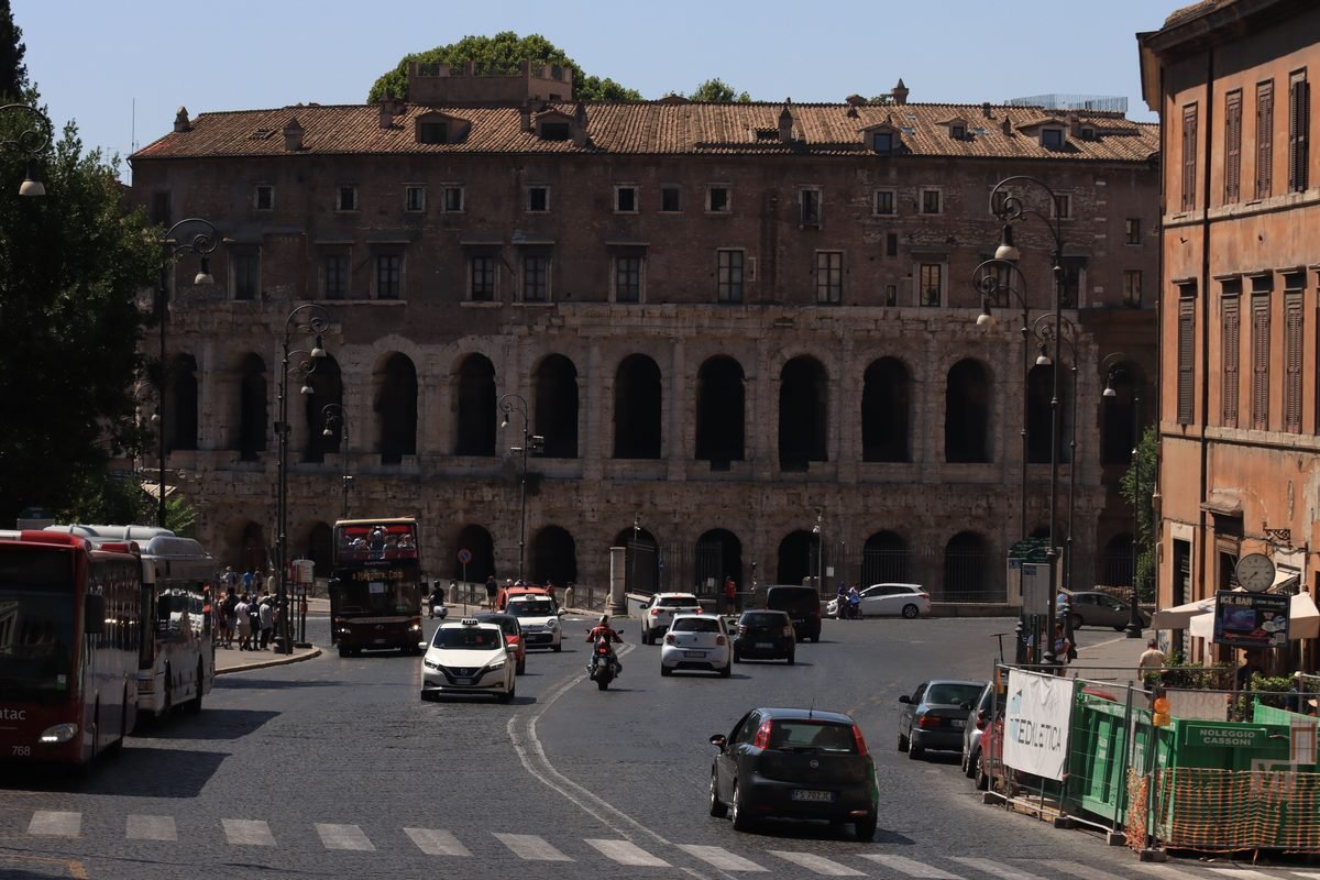 Traffic and buses moving through a historic street in Rome.