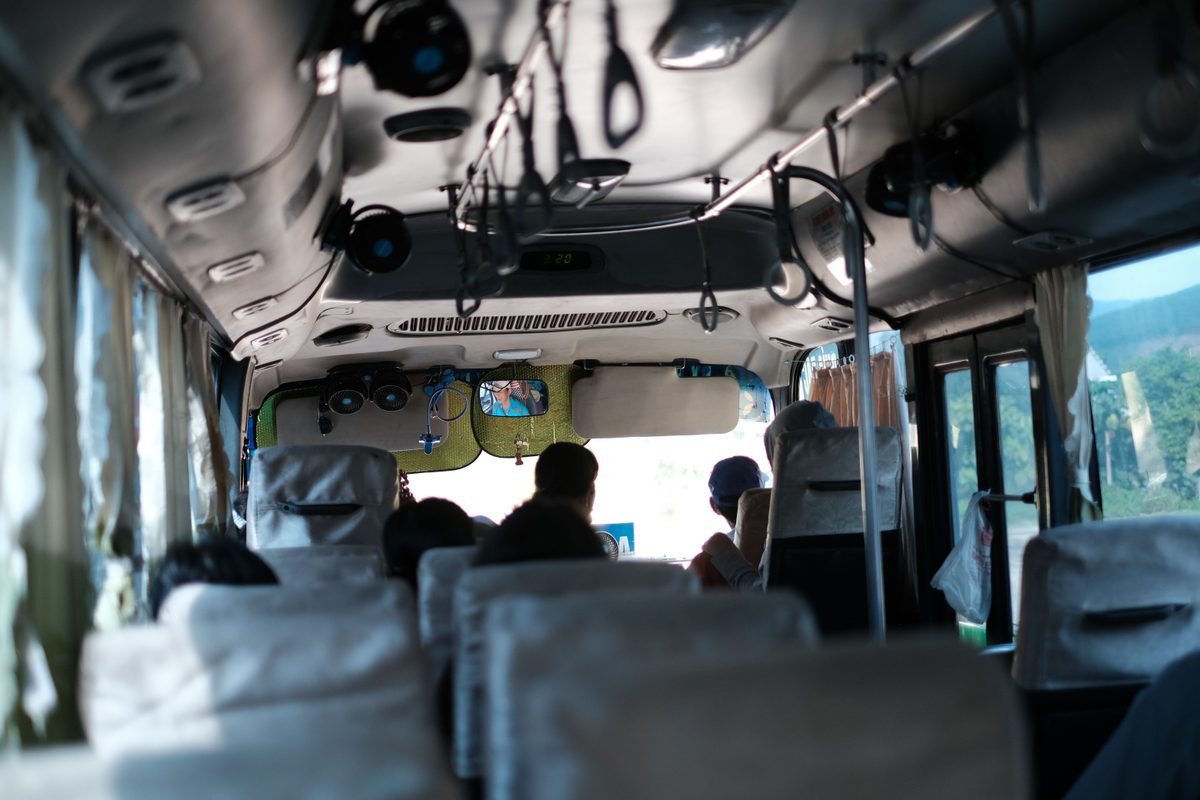 Interior of a Vietnamese bus with passengers and hanging straps.