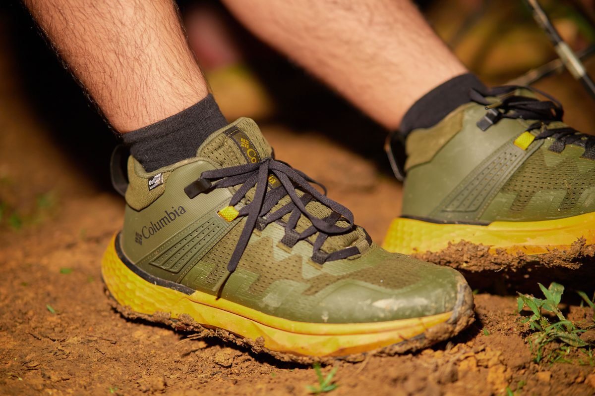 Close-up of green hiking shoes on a muddy trail.