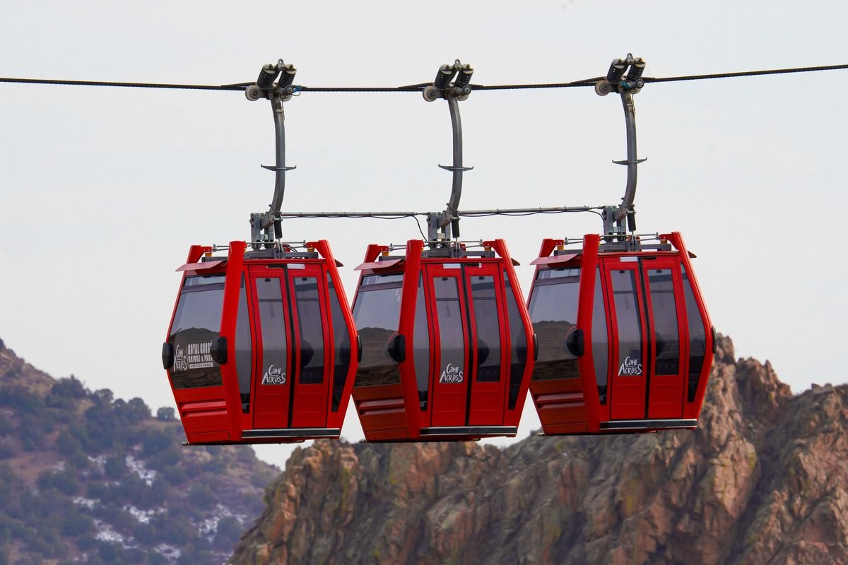 Red cable cars suspended against a mountainous landscape