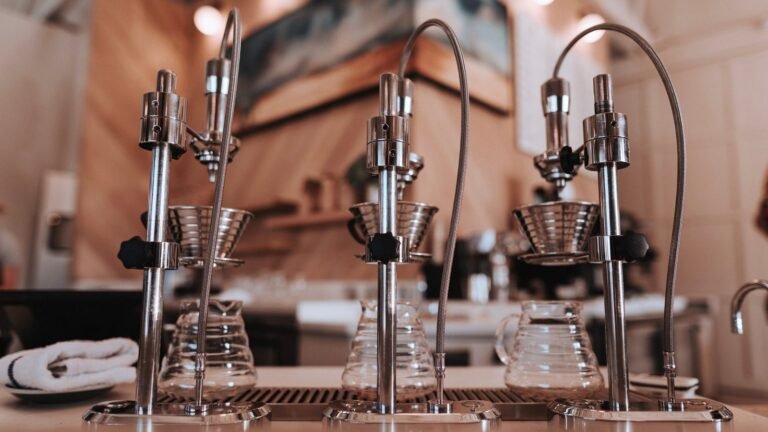A wooden coffee bar with specialty pour-over brewing equipment and seating inside a modern cafe.