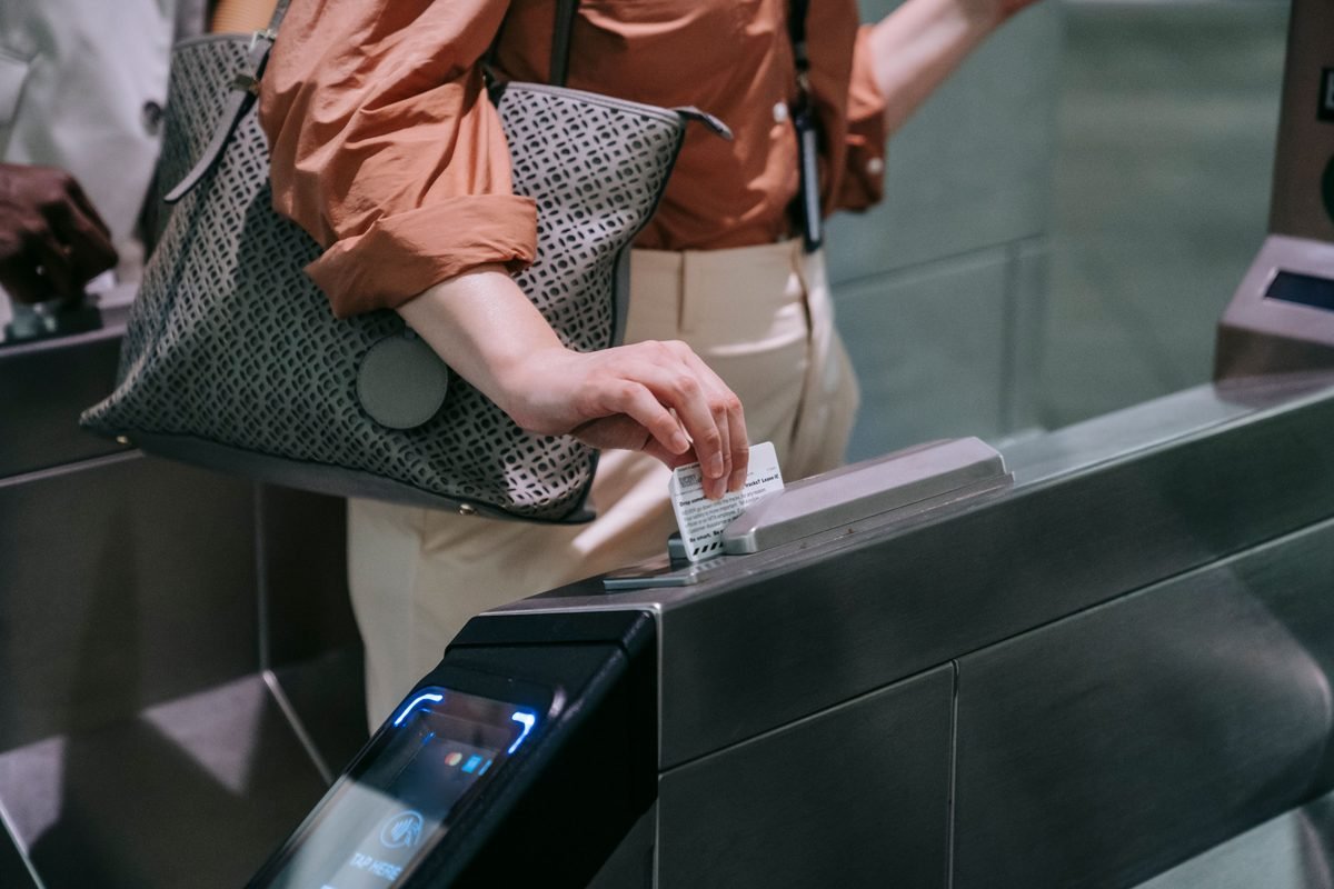 Close-up of a person using a ticket at a subway turnstile, showcasing a modern transport system.