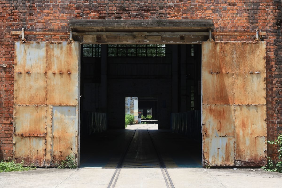 A rustic brick factory entrance with weathered metal doors.